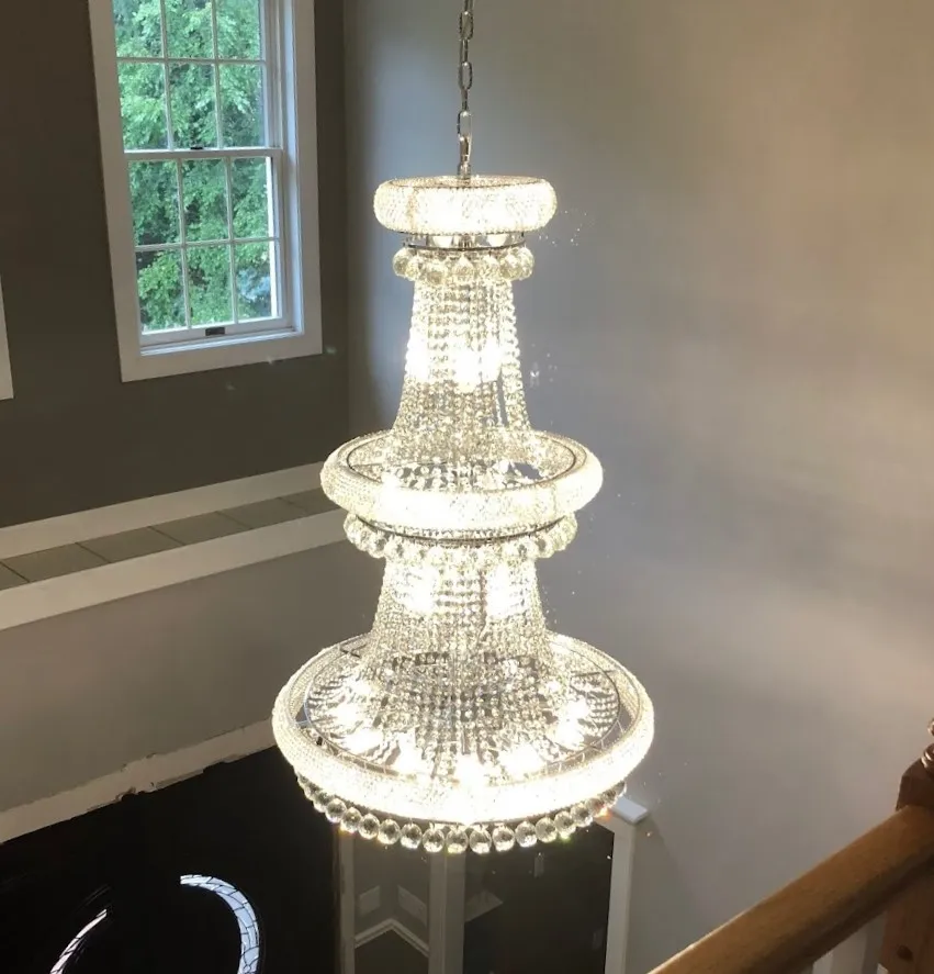 Illuminated tiered crystal chandelier above a staircase